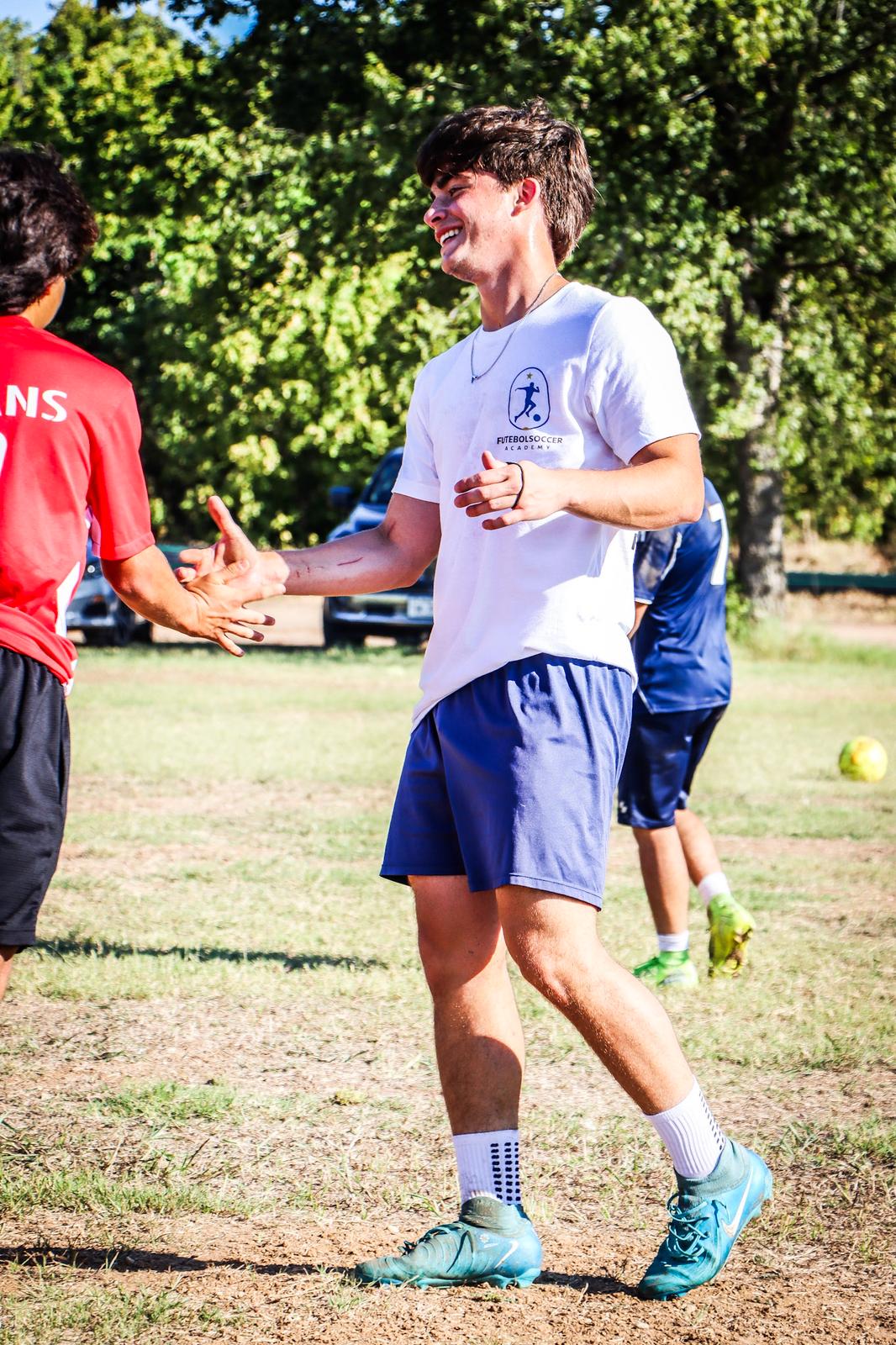 Coach Jose shaking hands with a player wearing a red shirt