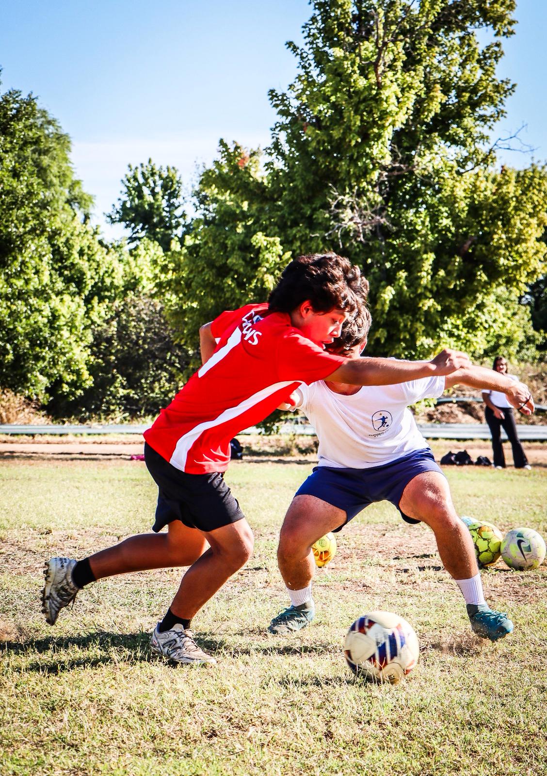 Coach Jose defending a player in a red shirt during a one-versus-one exercise